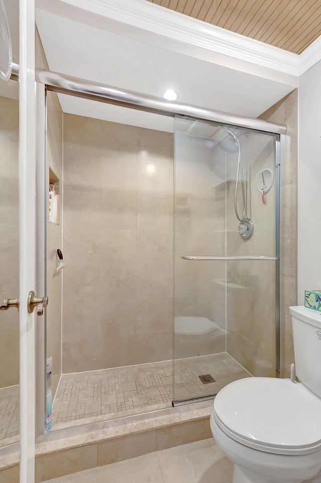 bathroom with crown molding, toilet, tile patterned flooring, and an enclosed shower