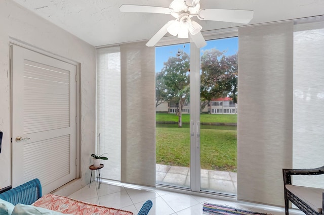 doorway to outside featuring floor to ceiling windows, light tile patterned floors, and ceiling fan