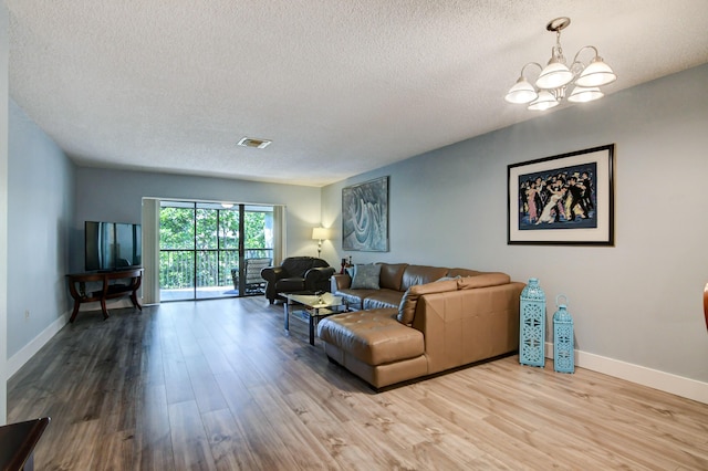 living room with hardwood / wood-style flooring, a textured ceiling, and an inviting chandelier