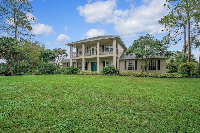 view of front of house featuring a balcony and a front lawn