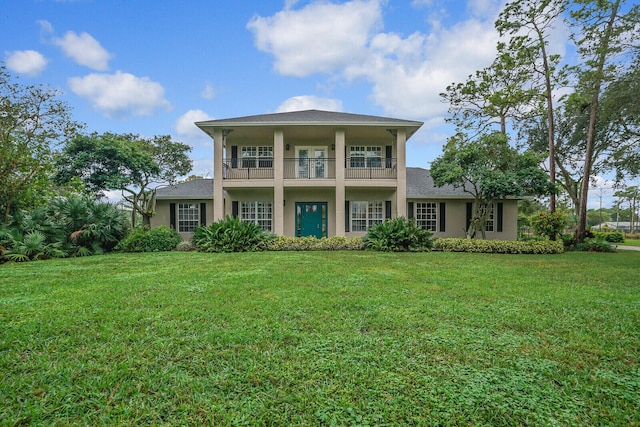 rear view of property featuring a balcony and a lawn