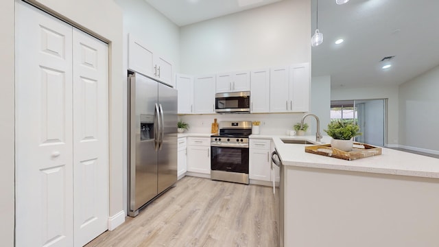 kitchen featuring decorative light fixtures, sink, white cabinetry, and appliances with stainless steel finishes