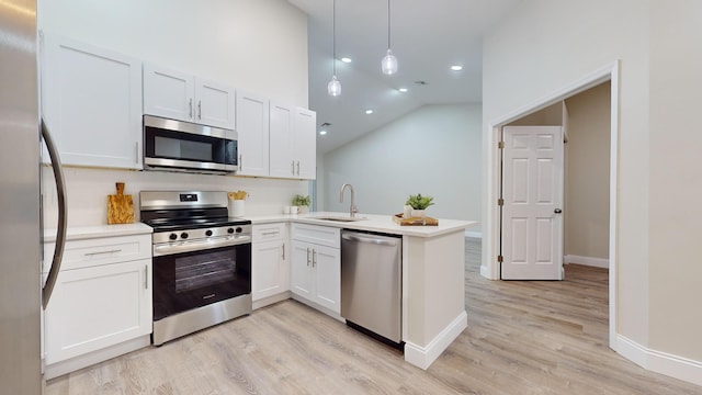 kitchen featuring white cabinets, stainless steel appliances, kitchen peninsula, and decorative light fixtures