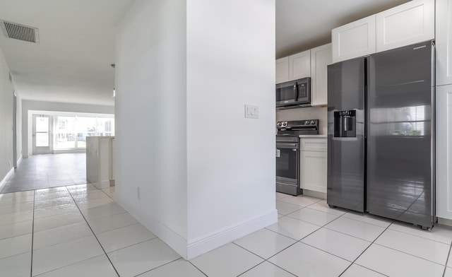 kitchen with white cabinets, light tile patterned floors, and appliances with stainless steel finishes