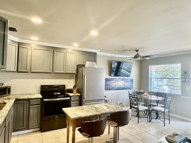 kitchen featuring crown molding, ceiling fan, light tile patterned floors, light stone counters, and stainless steel appliances