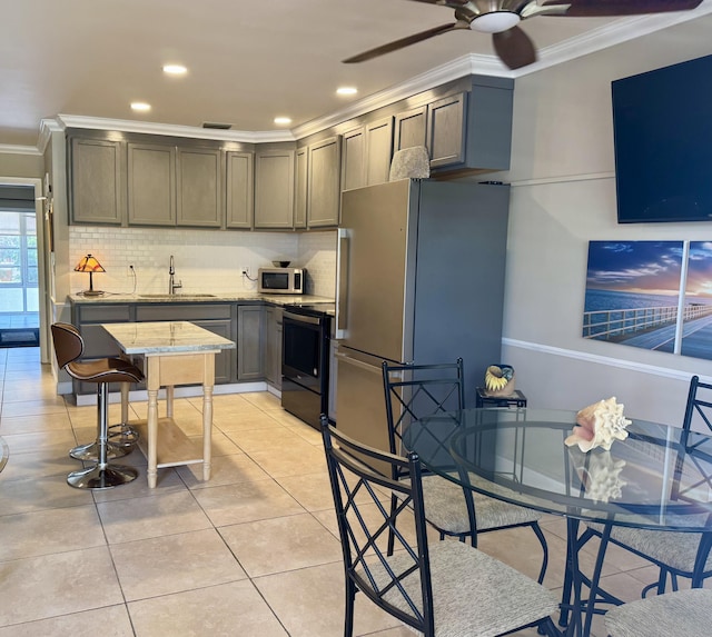 kitchen with light tile patterned floors, sink, appliances with stainless steel finishes, and crown molding