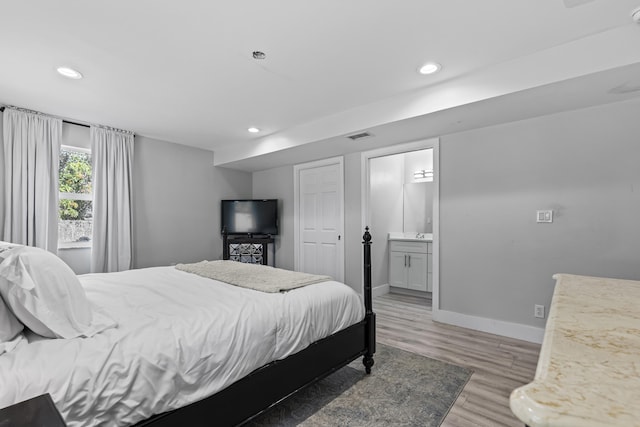 bedroom with ensuite bathroom and light wood-type flooring