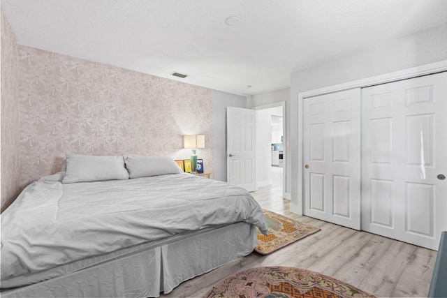 bedroom with light hardwood / wood-style floors and a closet