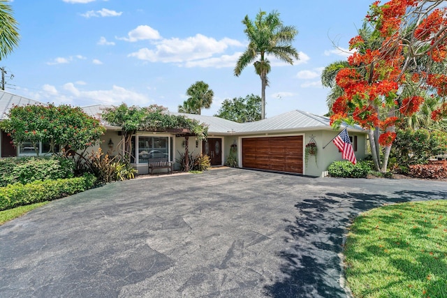 ranch-style house featuring a garage, aphalt driveway, metal roof, and stucco siding