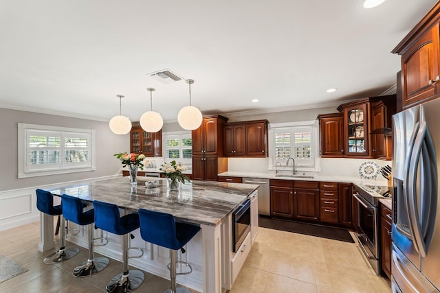 kitchen with pendant lighting, sink, a center island, a breakfast bar area, and stainless steel appliances