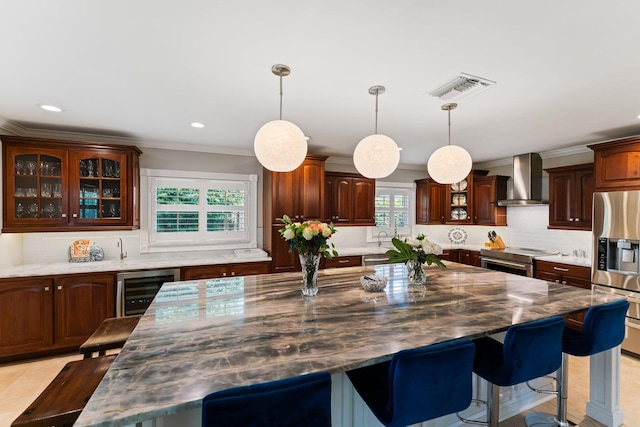 kitchen featuring tasteful backsplash, wall chimney range hood, a breakfast bar, stainless steel appliances, and beverage cooler