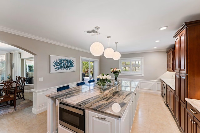 kitchen with crown molding, white cabinets, a center island, and stainless steel microwave