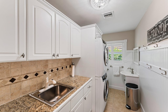 washroom featuring sink, stacked washing maching and dryer, and light tile patterned flooring