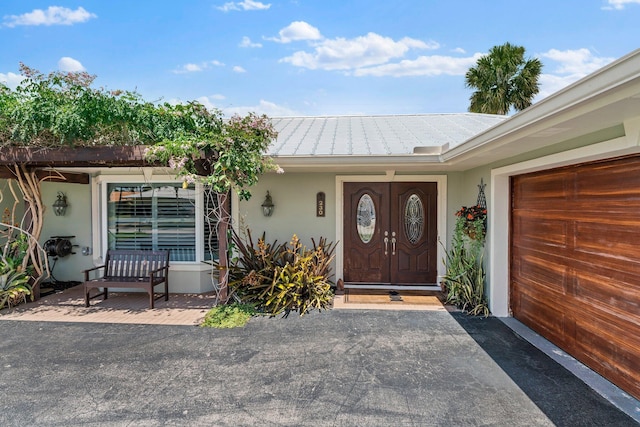 doorway to property featuring stucco siding, metal roof, an attached garage, and a standing seam roof