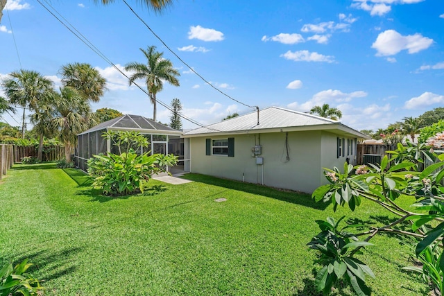 rear view of property featuring a lanai and a yard