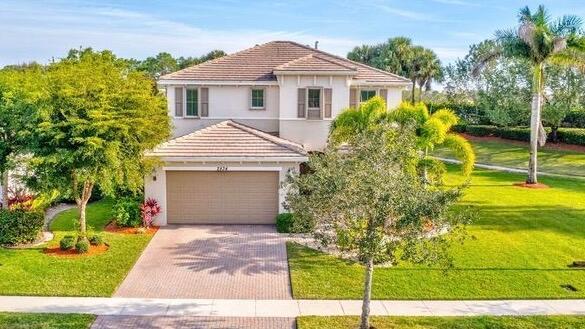 view of front of house featuring a tile roof, a front lawn, decorative driveway, and stucco siding