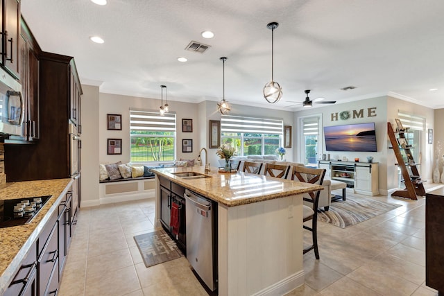 kitchen featuring dishwasher, sink, hanging light fixtures, a kitchen island with sink, and light stone counters