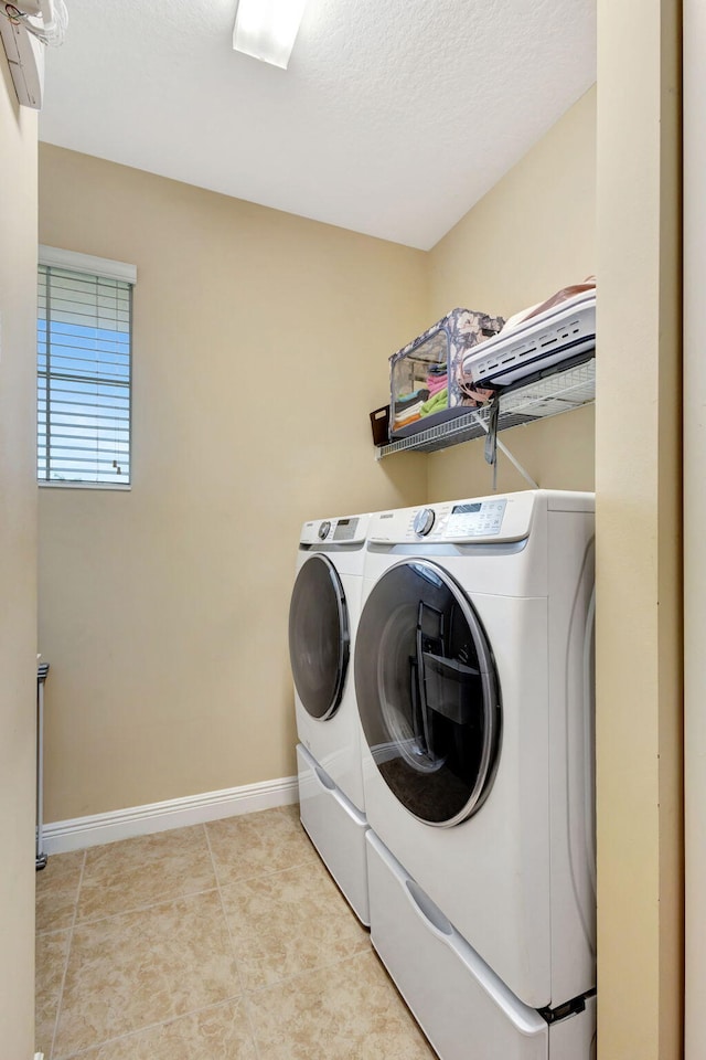 washroom featuring washing machine and dryer, light tile patterned flooring, and a textured ceiling