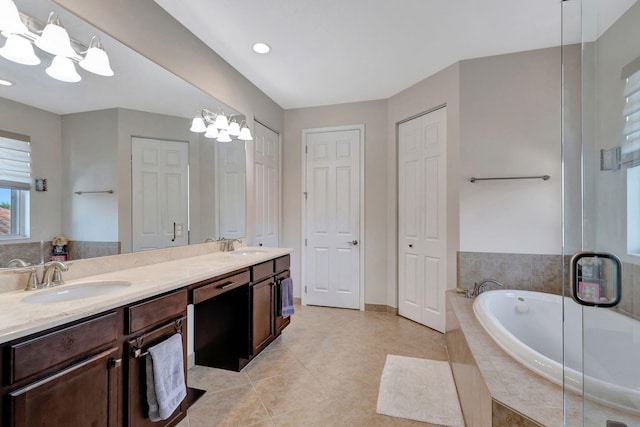 bathroom featuring tile patterned floors, vanity, tiled bath, and a notable chandelier