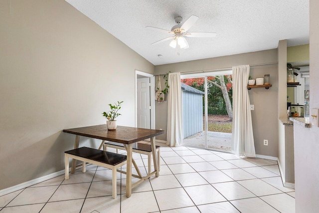 dining space with ceiling fan, a textured ceiling, lofted ceiling, and light tile patterned flooring