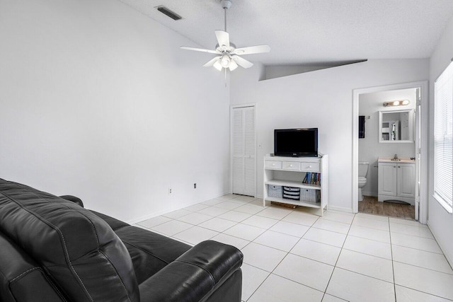 living room with vaulted ceiling, plenty of natural light, a textured ceiling, and light tile patterned flooring