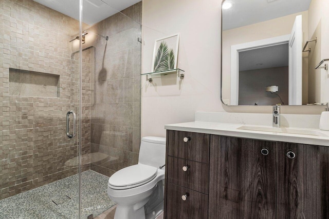 bathroom with a shower with door, vanity, and toilet