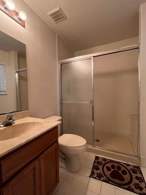 bathroom featuring vanity, toilet, a shower with door, and tile patterned flooring