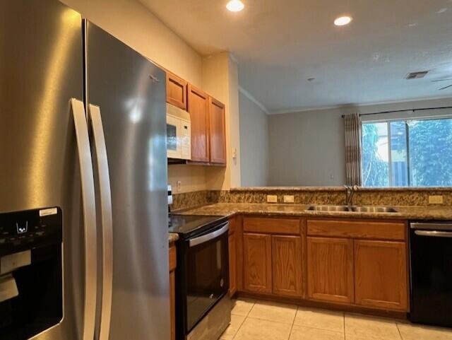 kitchen featuring sink, light tile patterned floors, and black appliances