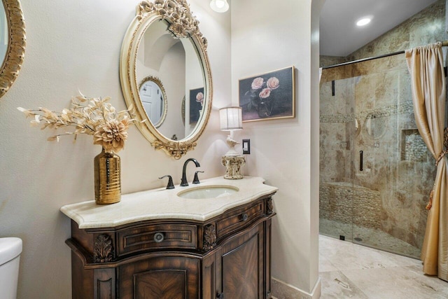 bathroom with tiled shower, vanity, and toilet