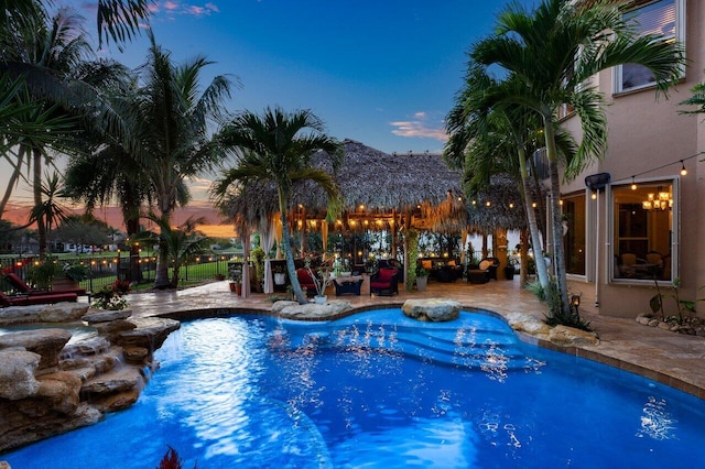 pool at dusk featuring a patio area