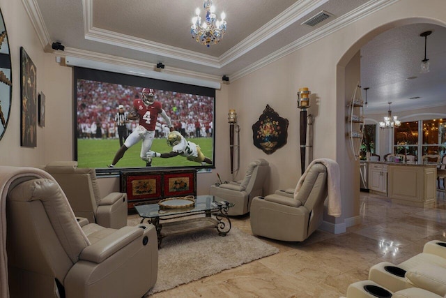 home theater featuring an inviting chandelier, a tray ceiling, ornamental molding, and a textured ceiling