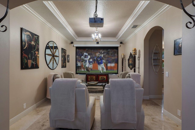 cinema room with ornamental molding, a raised ceiling, and a textured ceiling