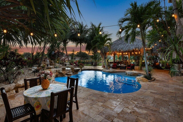 pool at dusk with a patio and a gazebo