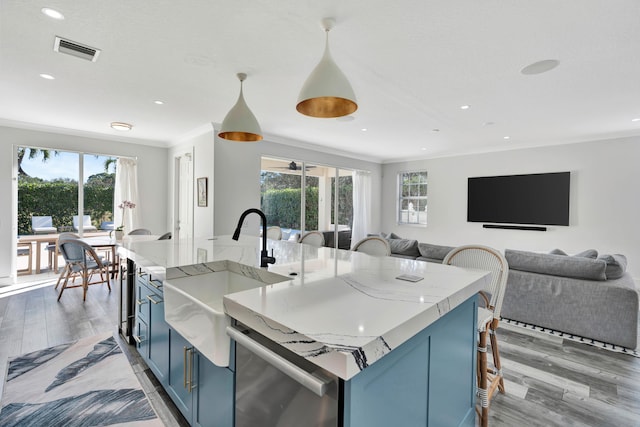 kitchen with a large island, sink, hanging light fixtures, blue cabinets, and stainless steel dishwasher