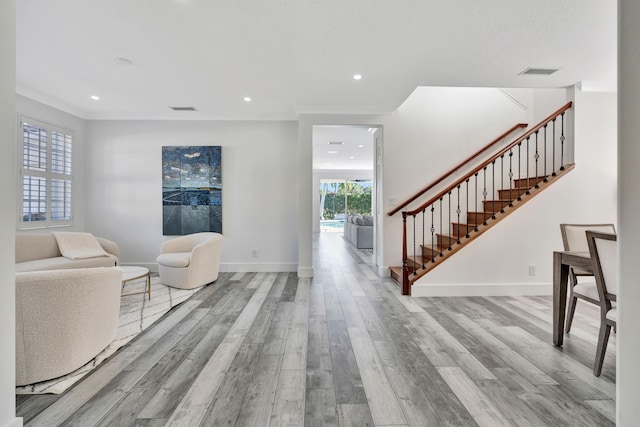 entryway with crown molding and light hardwood / wood-style flooring