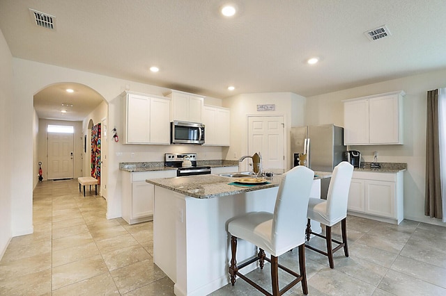 kitchen with sink, white cabinetry, a center island with sink, and appliances with stainless steel finishes