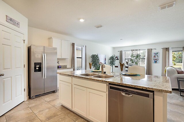 kitchen featuring white cabinetry, a healthy amount of sunlight, a kitchen island with sink, and appliances with stainless steel finishes