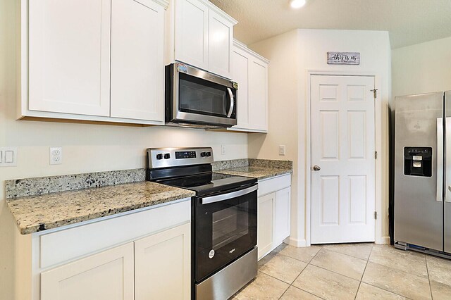 kitchen with white cabinetry, light stone counters, light tile patterned floors, and appliances with stainless steel finishes