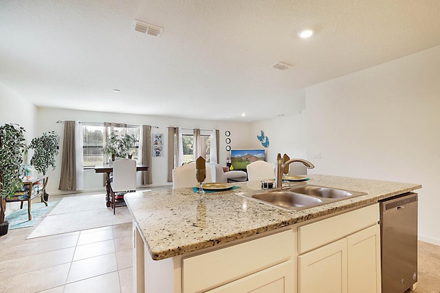 kitchen featuring sink, dishwasher, light stone counters, and a center island with sink