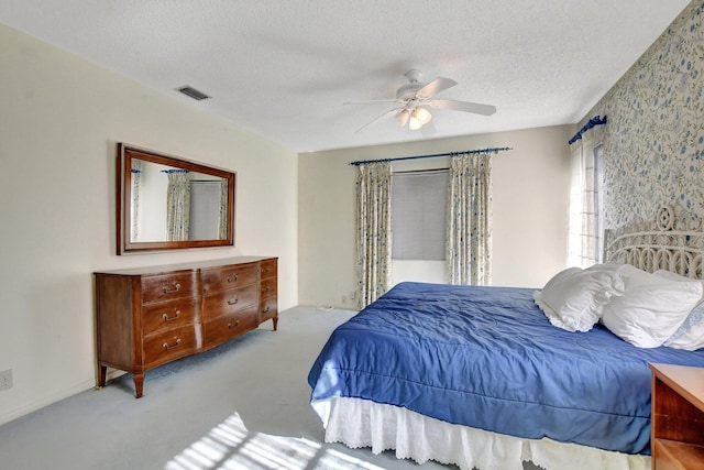 bedroom with light colored carpet, a textured ceiling, and ceiling fan
