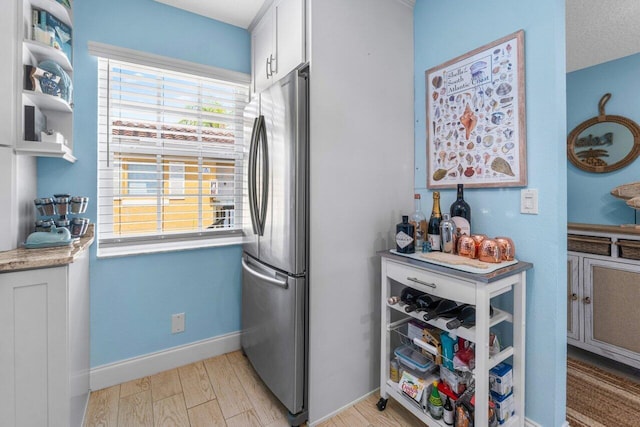 kitchen featuring white cabinetry, light wood-type flooring, a textured ceiling, and stainless steel refrigerator