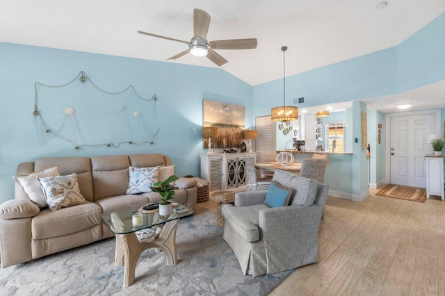 living room featuring ceiling fan with notable chandelier, light hardwood / wood-style flooring, and vaulted ceiling