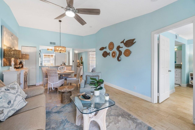 living room featuring ceiling fan with notable chandelier and light hardwood / wood-style flooring