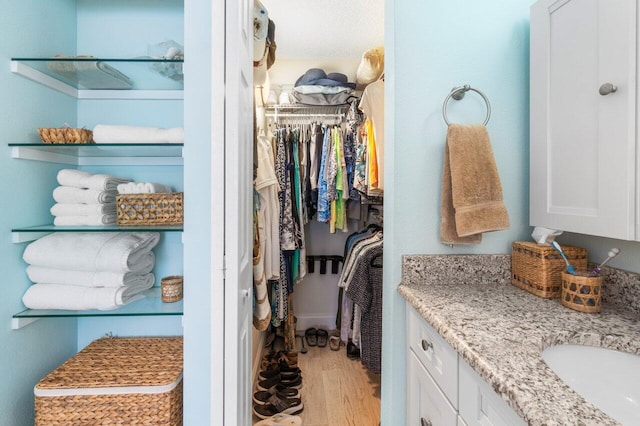 walk in closet featuring sink and light hardwood / wood-style flooring