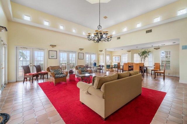 tiled living room with a notable chandelier, a towering ceiling, and french doors