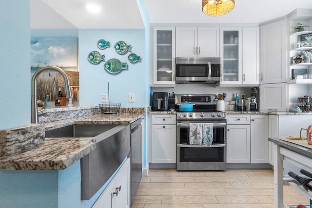 kitchen featuring light hardwood / wood-style floors, white cabinetry, appliances with stainless steel finishes, and a textured ceiling