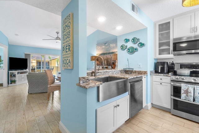 kitchen with sink, white cabinetry, stone counters, and appliances with stainless steel finishes