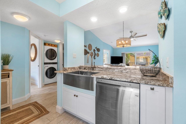 kitchen with a textured ceiling, white cabinetry, dishwasher, and stacked washer and clothes dryer