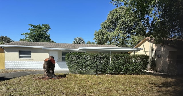 view of front of property with a front yard, brick siding, and stucco siding