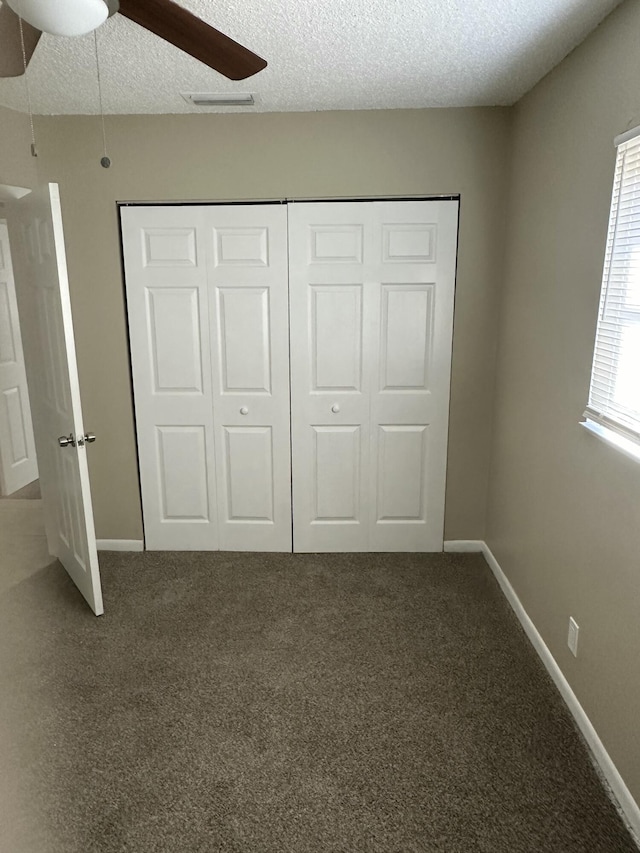 unfurnished bedroom featuring visible vents, a textured ceiling, a closet, carpet floors, and baseboards